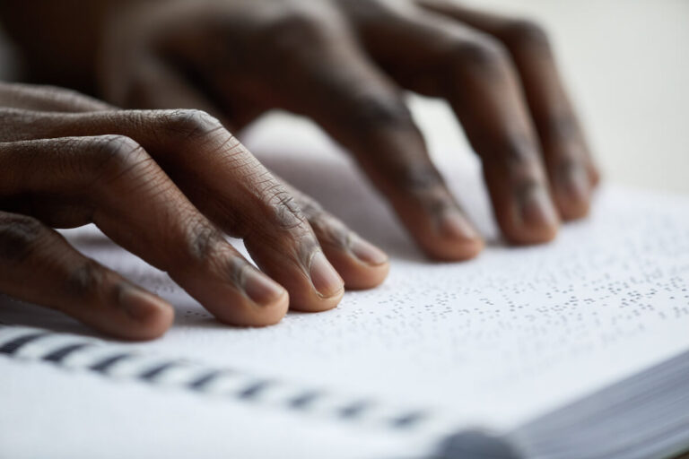 Person of color reading braille